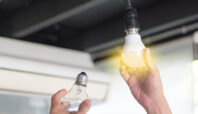 Power saving concept. Asia man changing compact-fluorescent (CFL) bulbs with new LED light bulb.