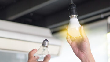 Power saving concept. Asia man changing compact-fluorescent (CFL) bulbs with new LED light bulb.